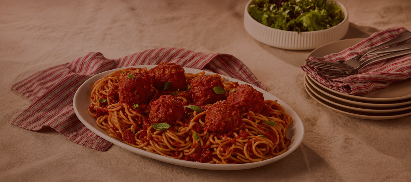 Rao's® spaghetti and meatballs topped with tomato sauce and fresh basil on a serving platter