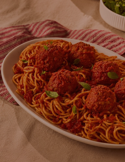 Rao's® spaghetti and meatballs topped with tomato sauce and fresh basil on a serving platter